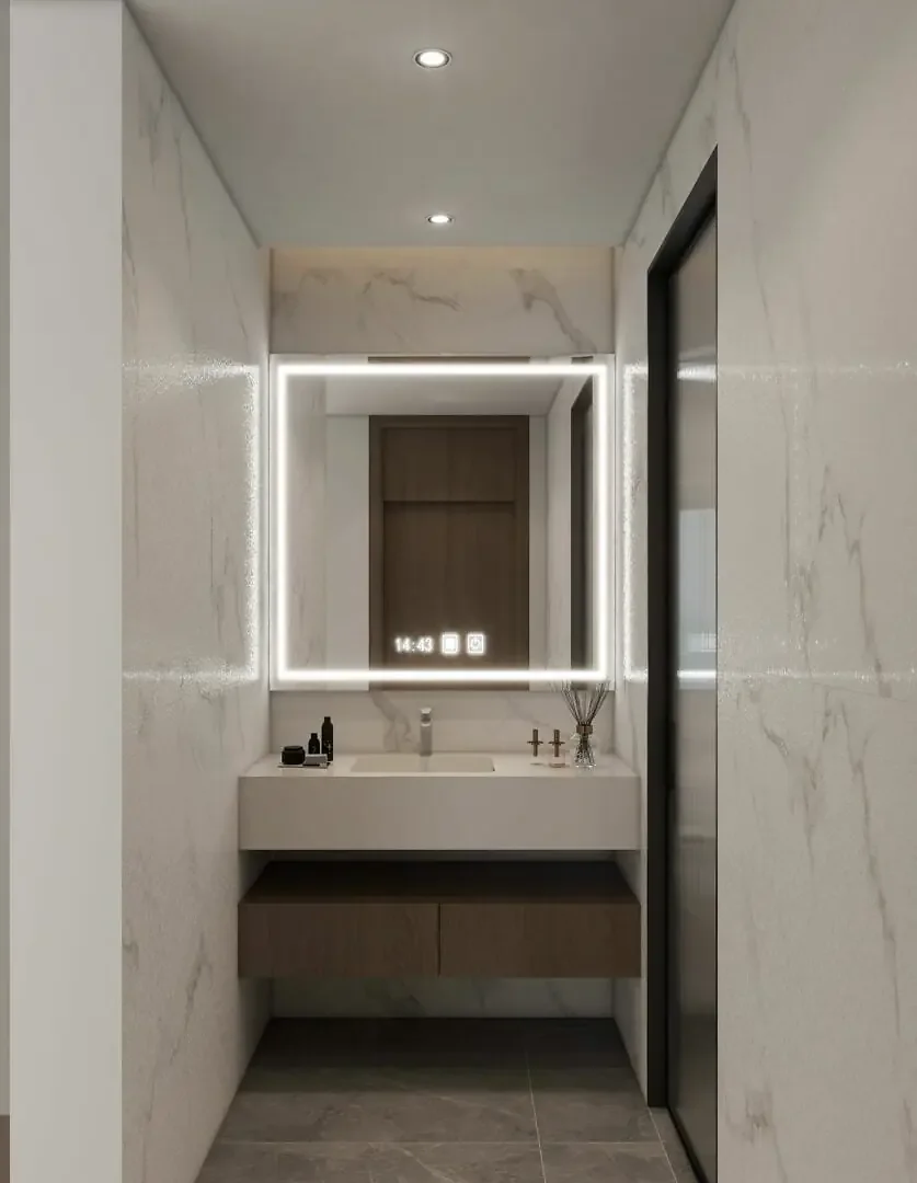 Bathroom vanity with an illuminated mirror, floating cabinet and marble-effect walls at Baraka Capital Residency.