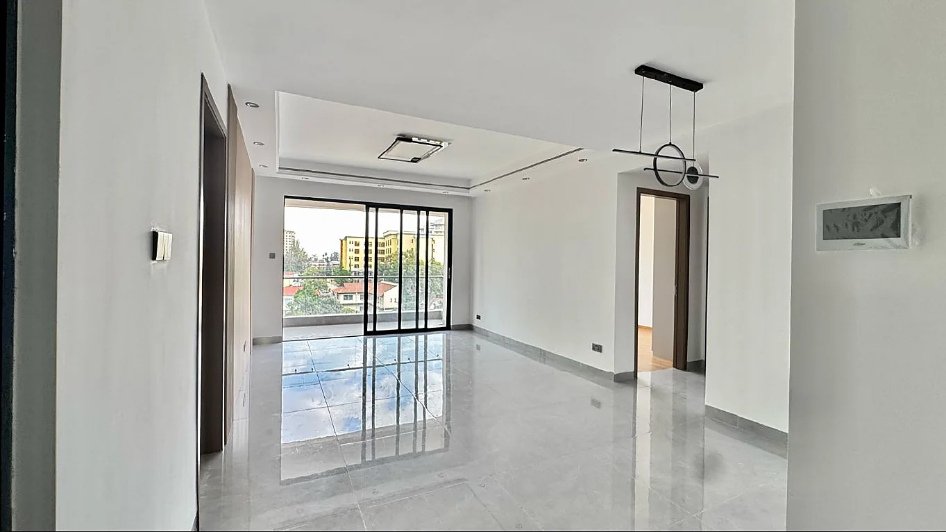 Unfurnished living area at Capital Garden, Hurlingham, with glossy floor tiles and sliding glass doors to a balcony.