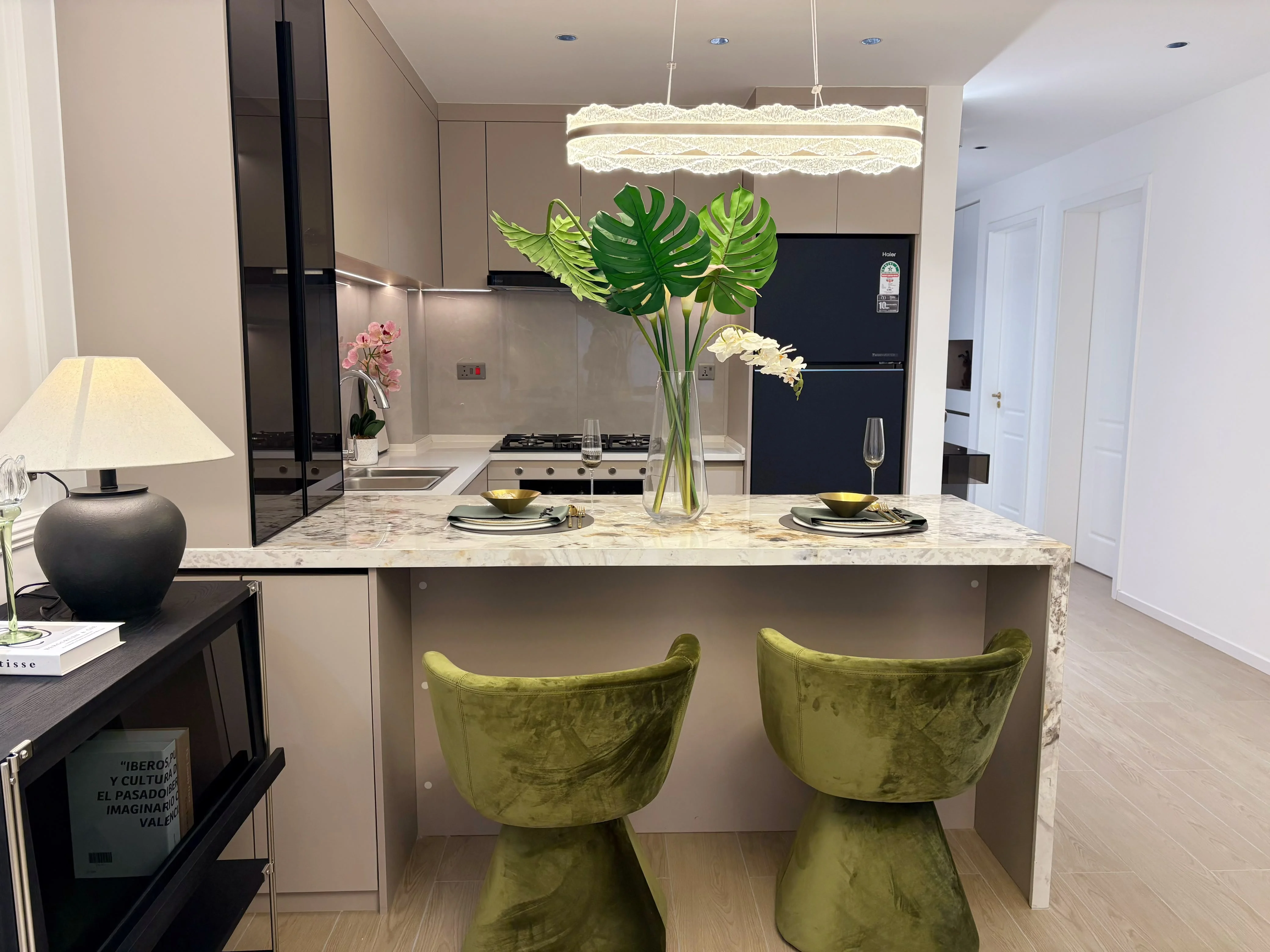Capital Heights Westlands kitchen with a breakfast bar, two green chairs and a pendant light.