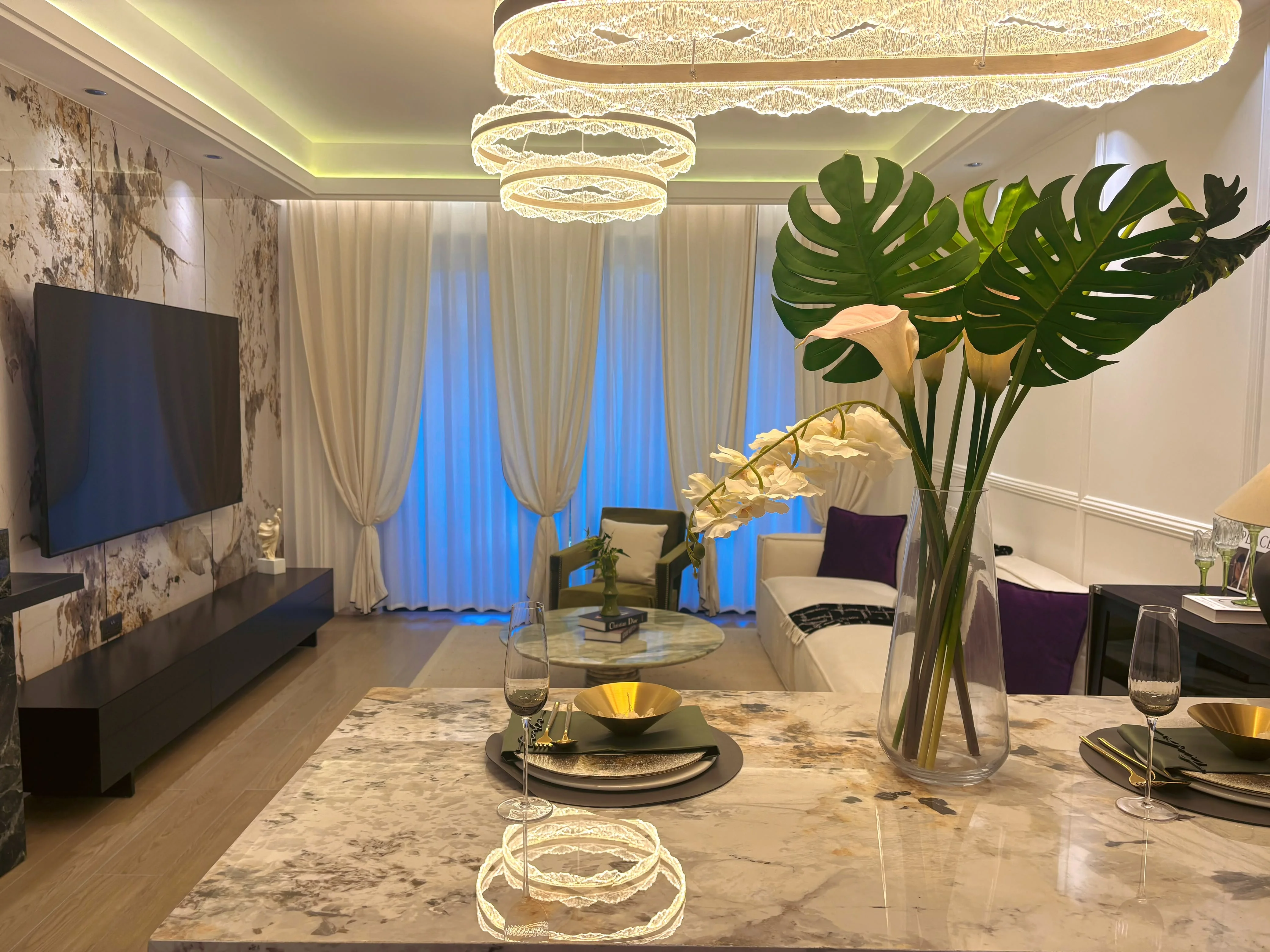 Capital Heights Westlands living and dining area with a set table, floral centrepiece, sofa and ring-shaped pendant lights.