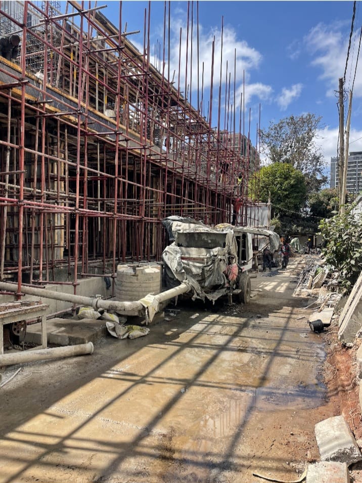 Scaffolding and construction equipment beside a muddy access path at Capital Vista in Kilimani.
