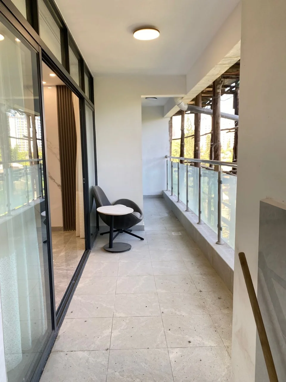 Tiled balcony with glass railing, chair and round table at Golden Street Residency, Kileleshwa.