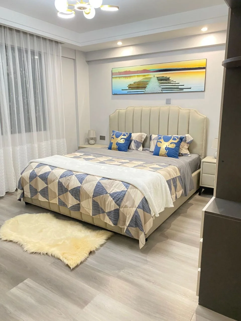 Bedroom at Golden Street Residency, Kileleshwa, with an upholstered headboard, geometric bedding and sheer curtains.