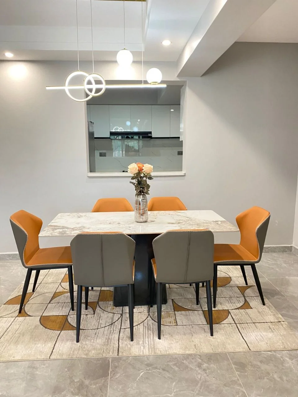 Dining area at Golden Street Residency with orange and grey chairs beneath a geometric pendant light.