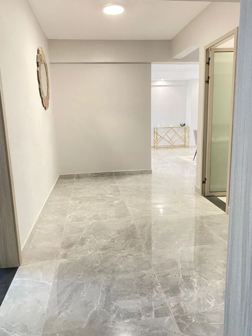 Hallway with glossy grey floor tiles and a round wall mirror at Golden Street Residency, Kileleshwa.