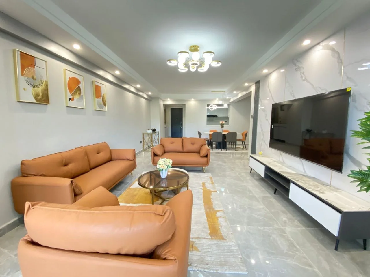 Living and dining area with orange sofas and wall-mounted TV at Golden Street Residency, Kileleshwa.