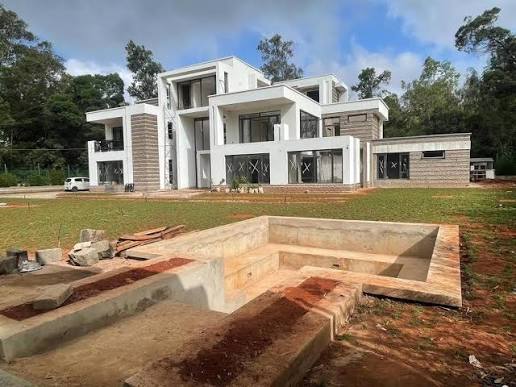 Hibo Manor villa in Karen, Nairobi, with white walls, balconies and a sunken concrete structure in front.