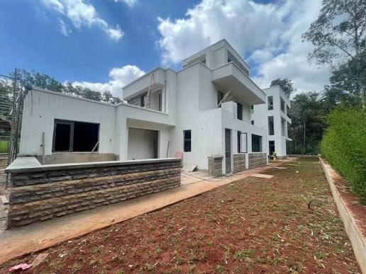 White multi-storey villa at Hibo Manor, Karen, with low stone walls and a hedge-lined yard.