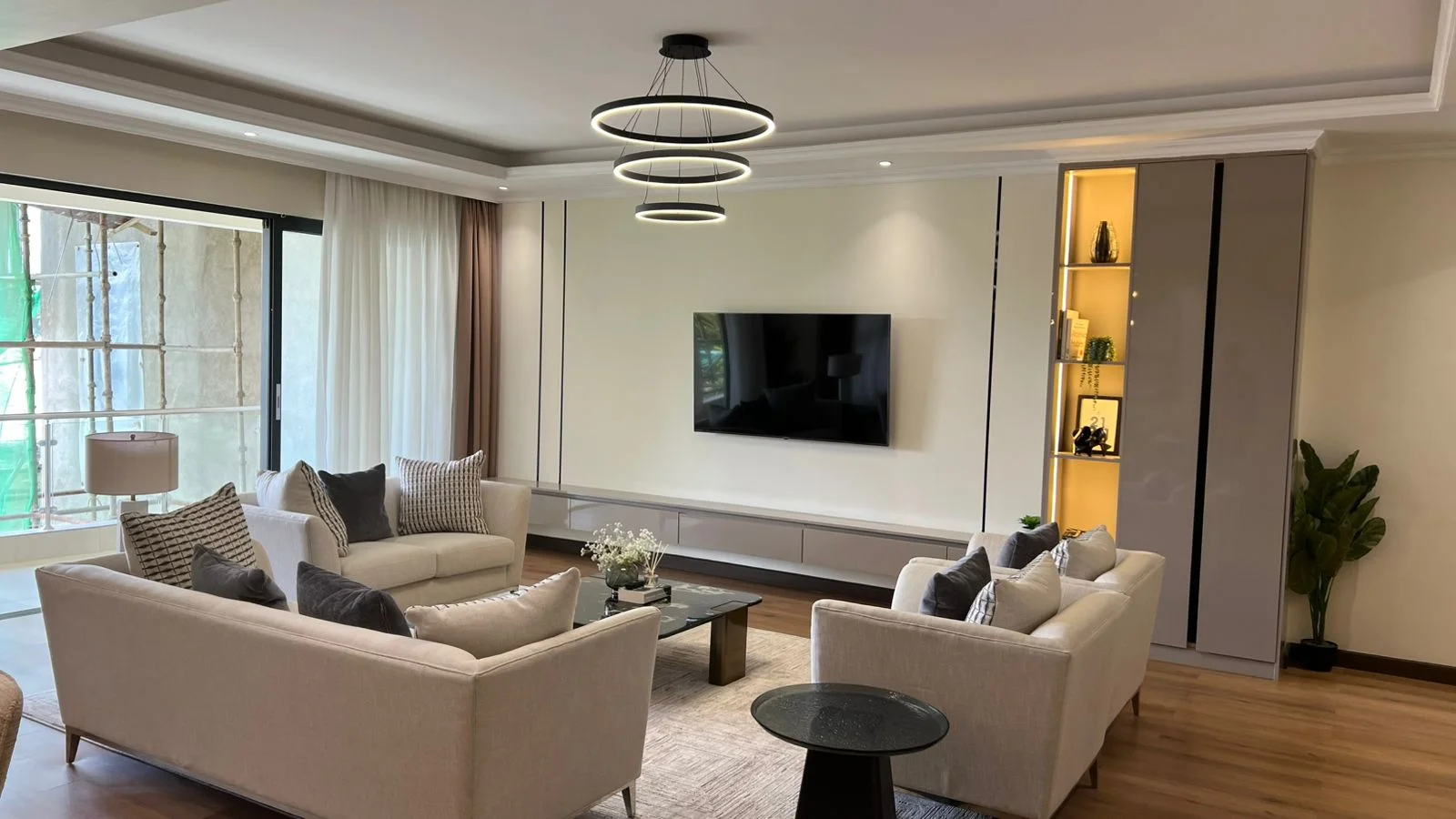 Living room in the Jabavu Road apartment, Kilimani, with cream sofas, wall-mounted television and circular pendant lights.