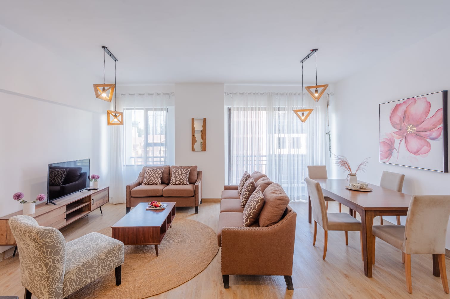 Kilimani apartment living and dining area with brown sofas, a dining table and geometric pendant lights.