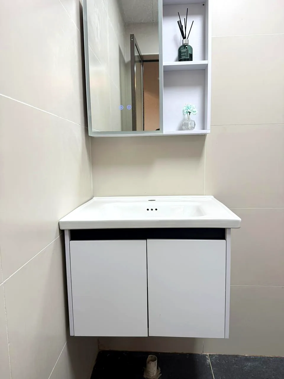 White wall-mounted bathroom vanity with mirror and open shelving at Lido Garden Apartments, Kilimani.