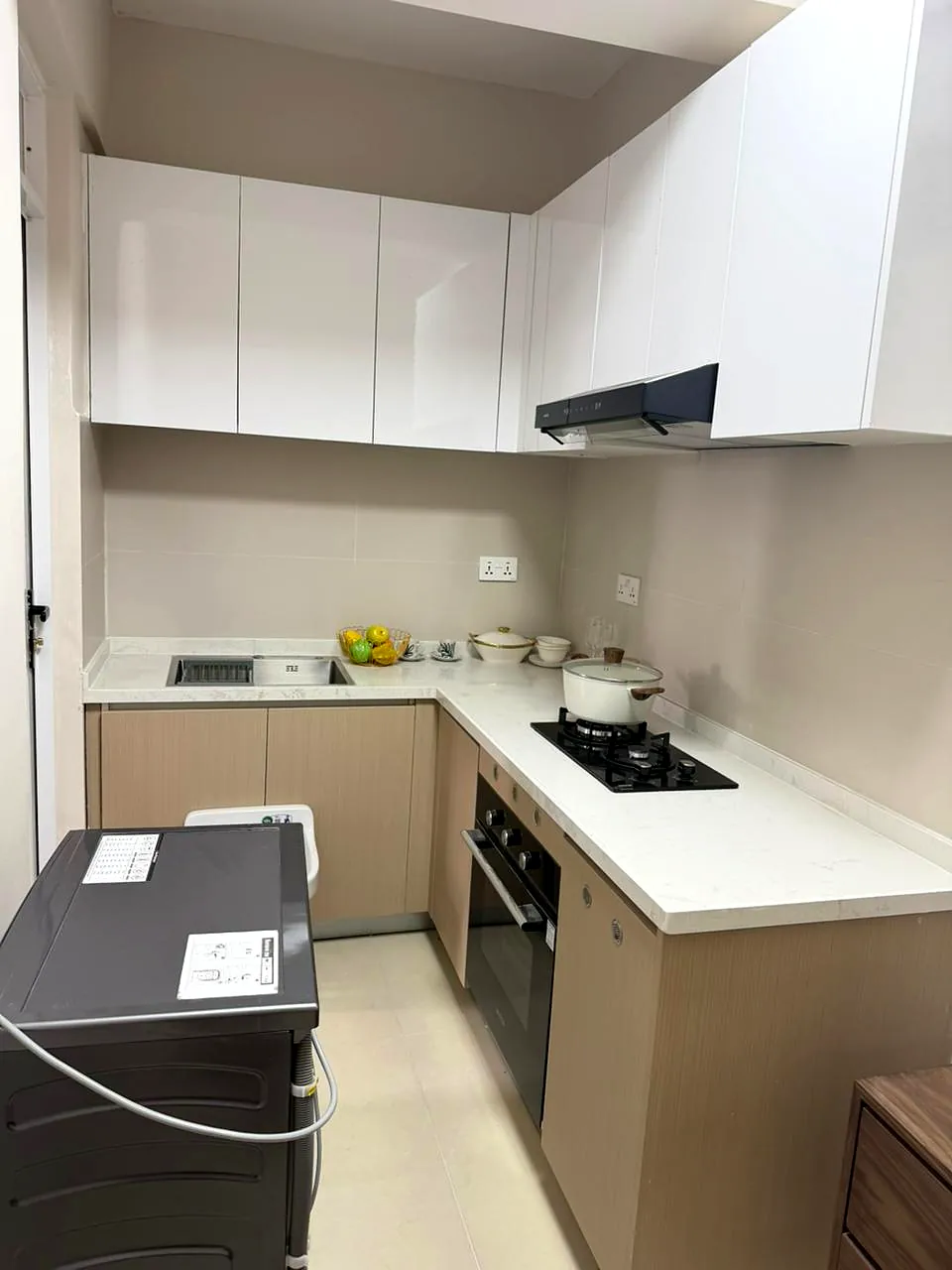 Lido Garden kitchen in Kilimani with white cabinets, L-shaped counters, sink, gas hob and built-in oven.