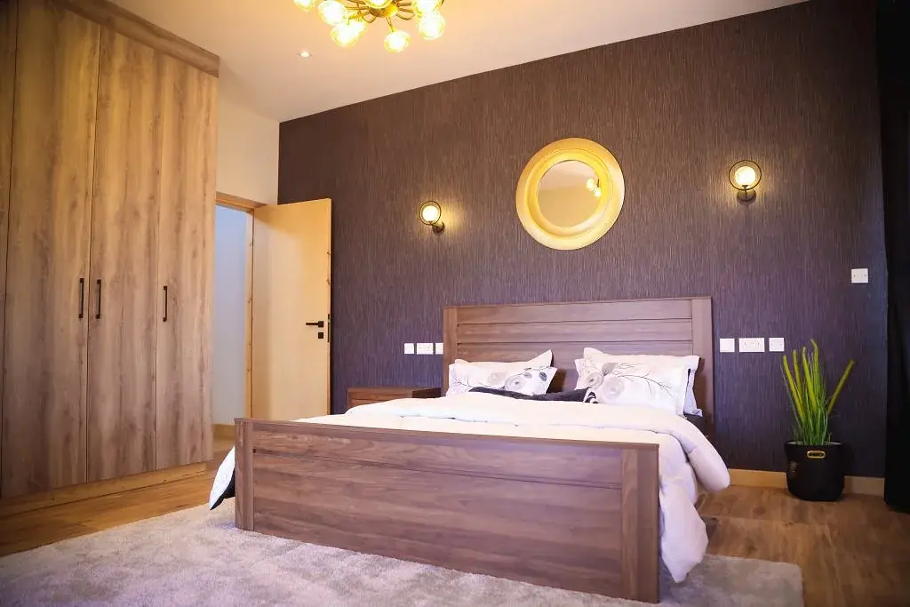 Bedroom at Marigold II in Langata with a wooden bed, tall wardrobe and dark accent wall.
