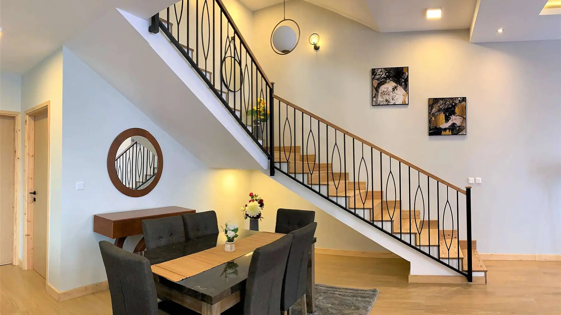 Dining table with dark upholstered chairs beside a black-railed staircase at Marigold II Residency, Langata.