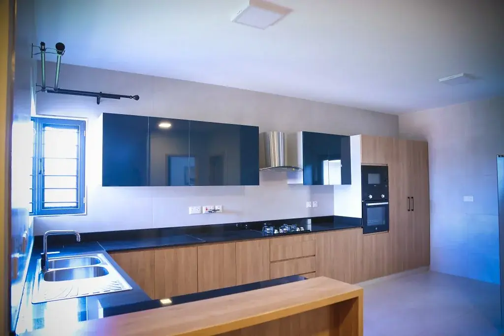Kitchen at Marigold II Langata with wood-tone cabinets, dark countertops, a double sink and built-in oven.
