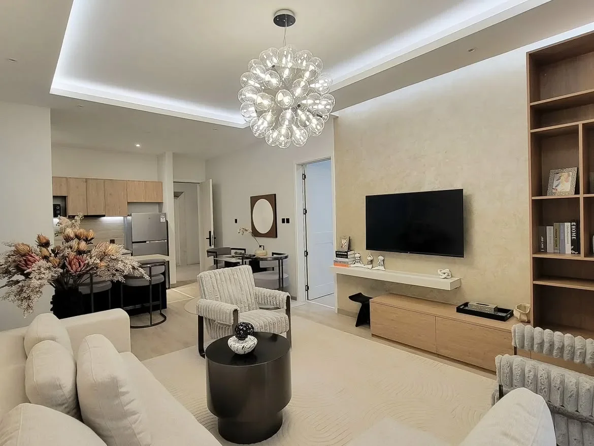 Ngong Road apartment living room with cream seating, a round coffee table and wall-mounted television.