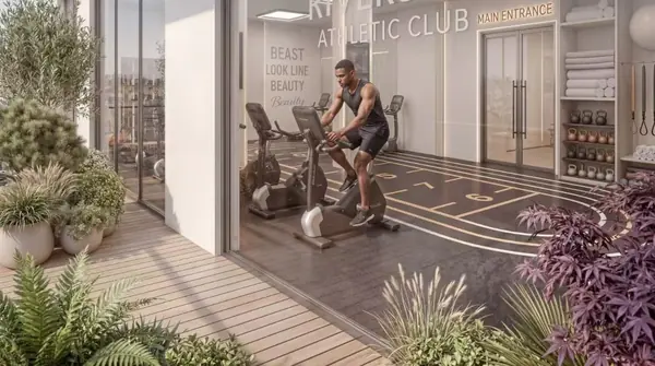 Riverside Times Apartments gym rendering with a man on an exercise bike beside floor-to-ceiling windows.
