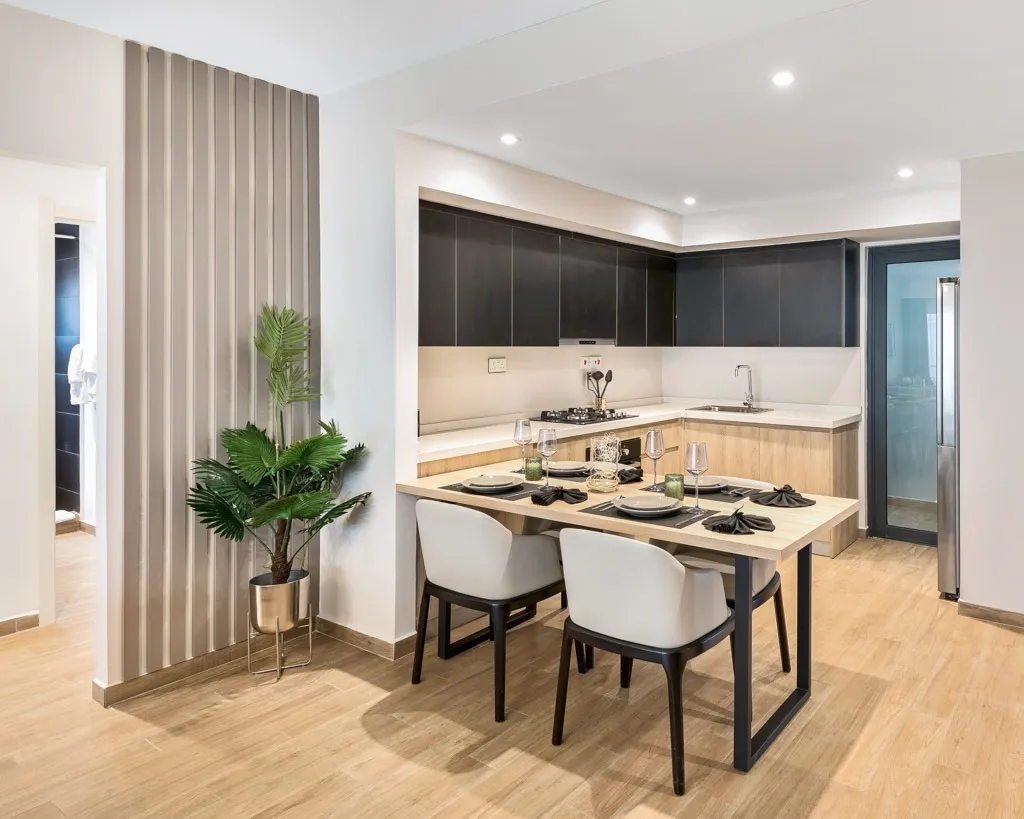 South C apartment kitchen with dark upper cabinets, white countertops and a dining table with place settings.