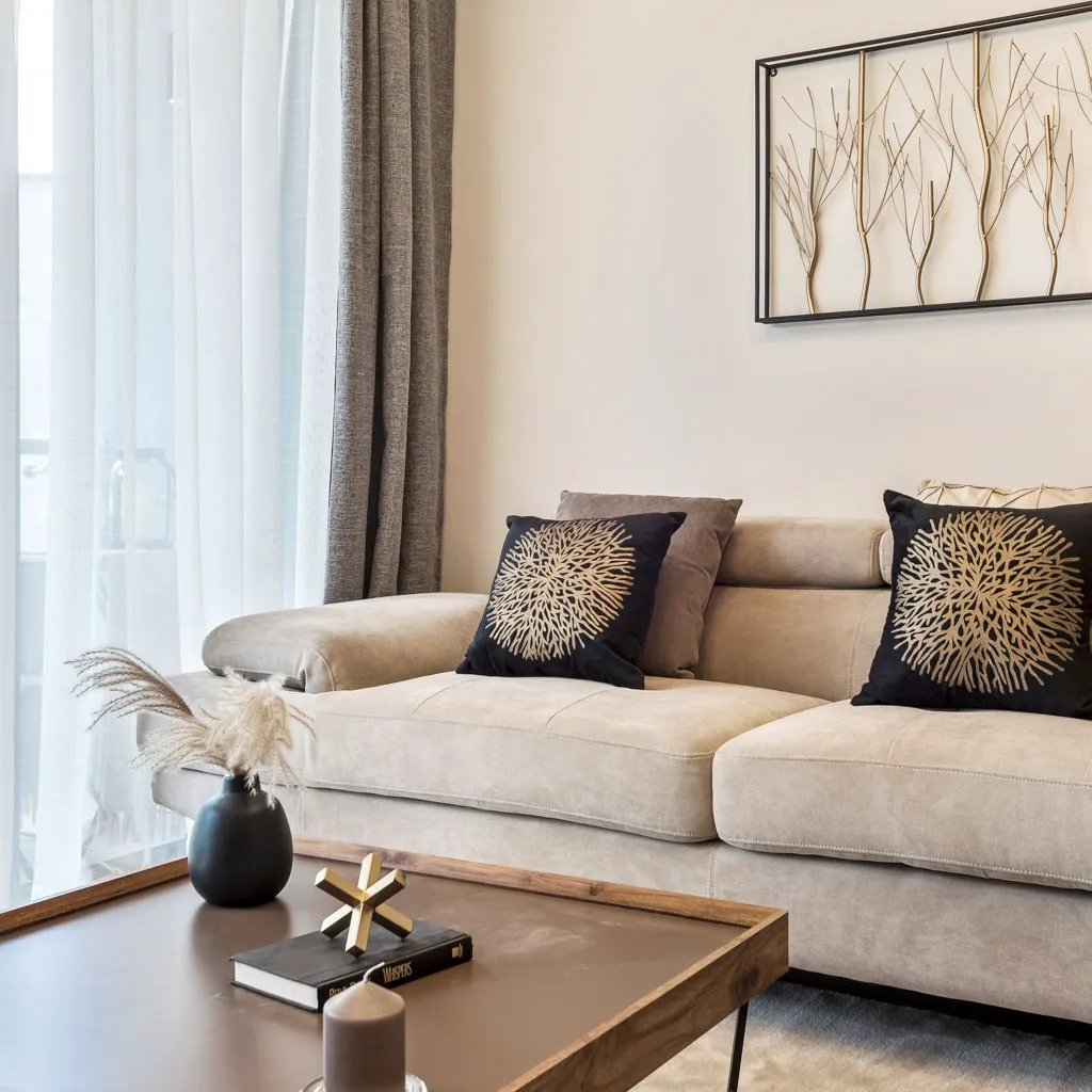 Beige sofa with patterned cushions, coffee table and framed branch artwork in a South C apartment.