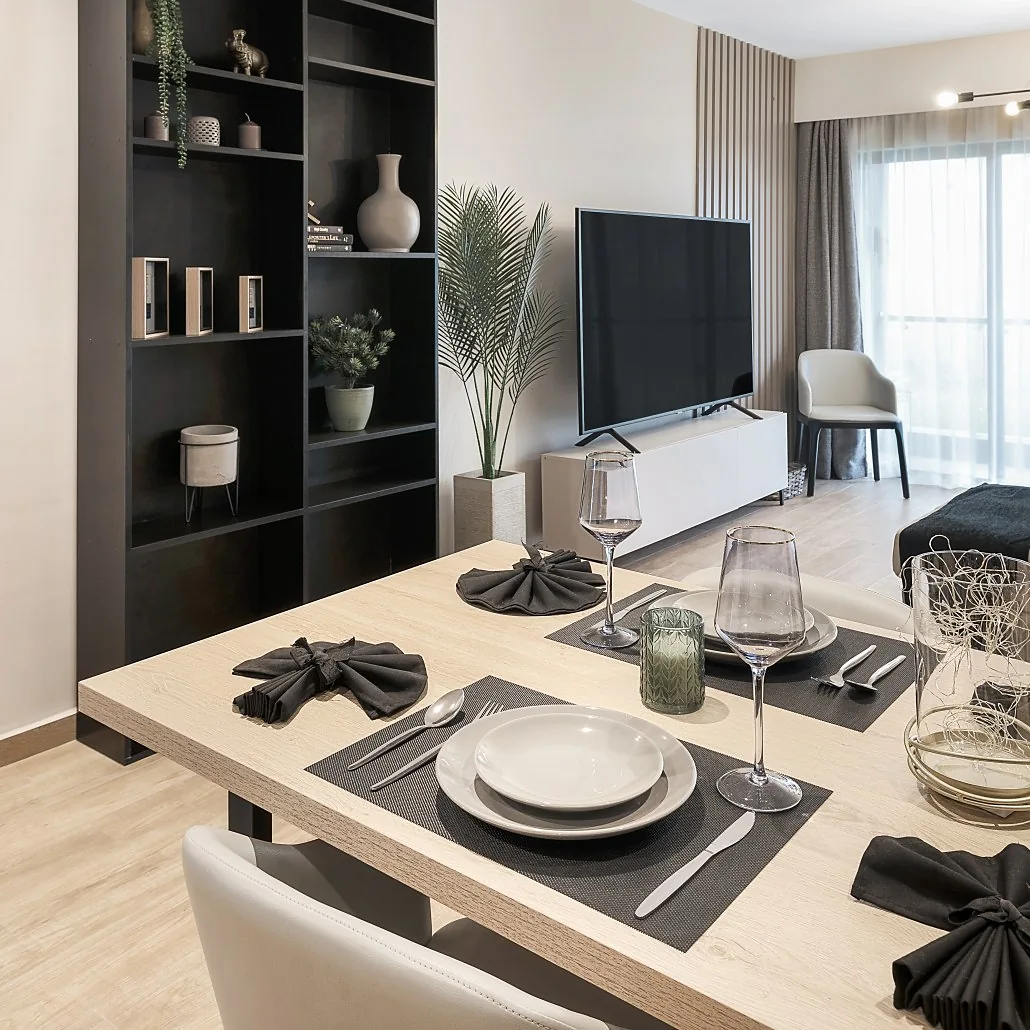 Dining table with place settings, dark display shelves and television at South Park Apartments, South C.