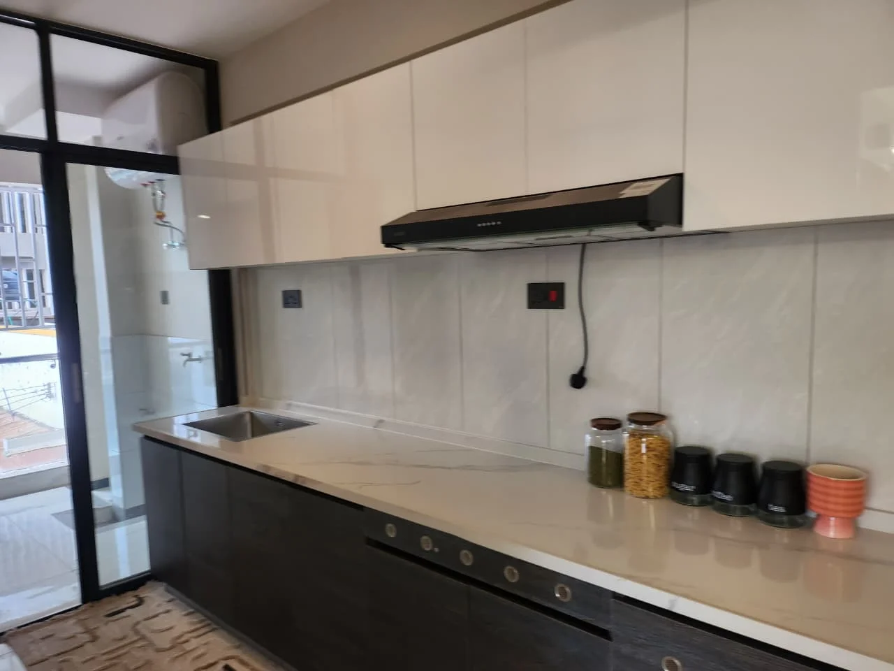 Kitchen at Super Westbury, Westlands, with white upper cabinets, dark lower cabinets, sink and extractor hood.