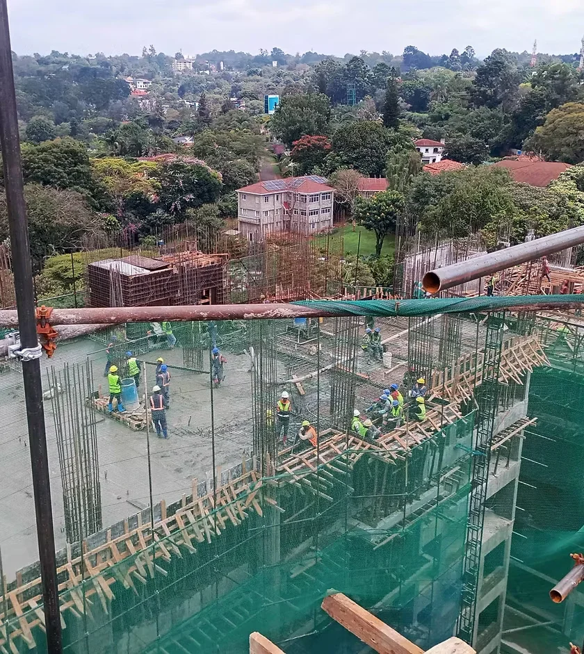 Workers on a concrete slab amid exposed rebar at Verona Apartments construction site in Westlands.